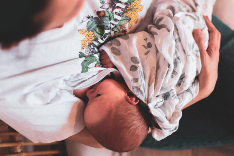 Maman allaitant son bébé en position couchée, lumière naturelle douce
